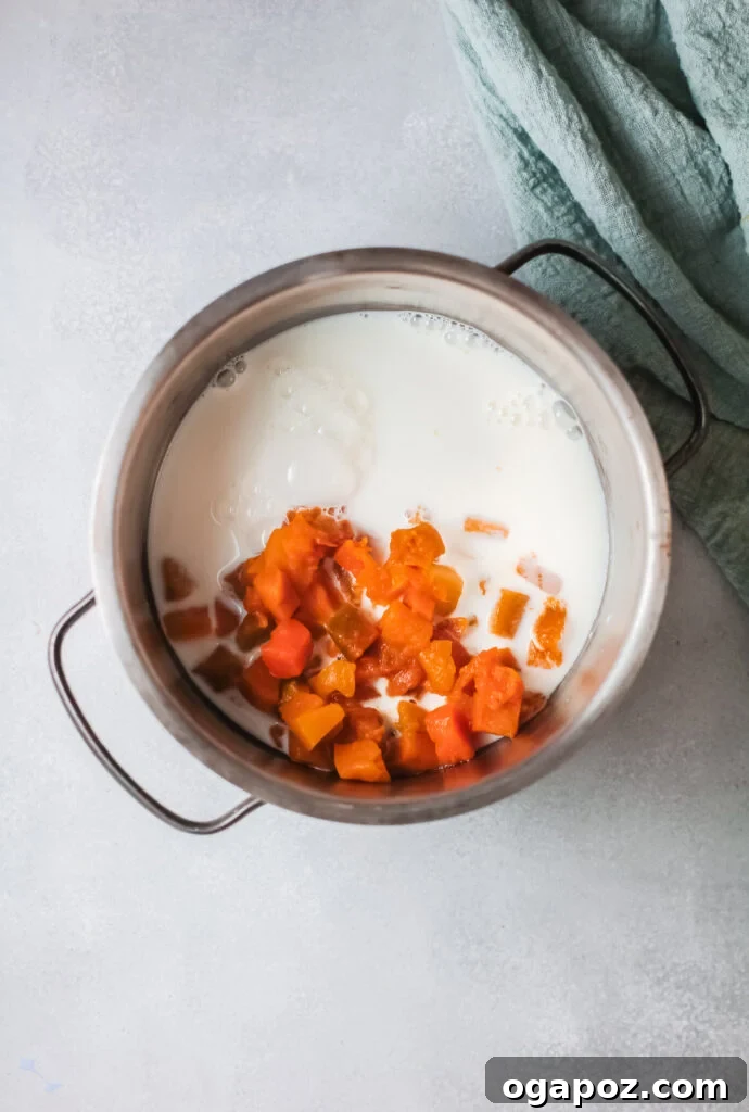 Cozy Pumpkin Oatmeal 5 A saucepan on a stovetop, showing milk being combined with fresh diced pumpkin, simmering to create the creamy base for pumpkin oatmeal.