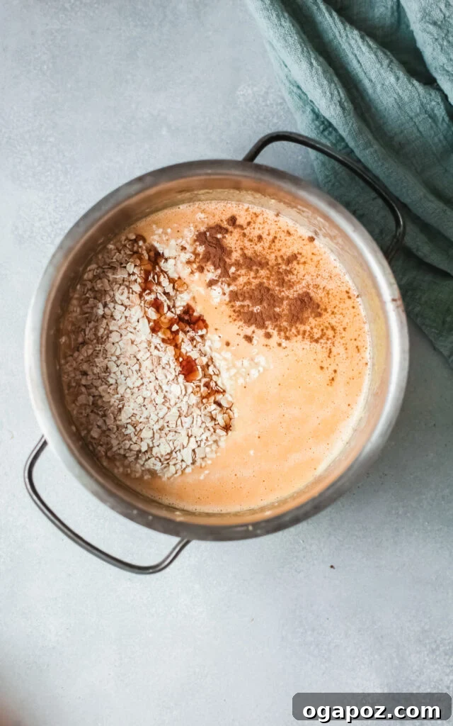 Cozy Pumpkin Oatmeal 6 Creamy pumpkin oatmeal simmering gently in a pot on the stove, showing its thickening consistency as it cooks to perfection.