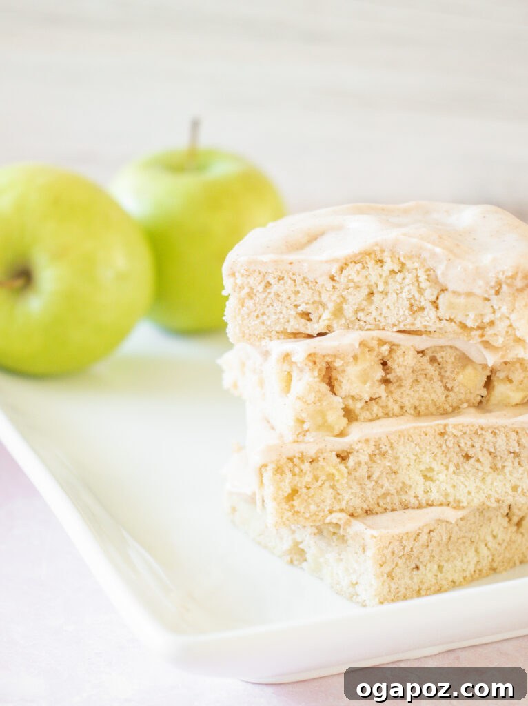 Autumn Apple Bars with Pumpkin Spice Glaze 4 A single perfectly baked and frosted Apple Bar with Pumpkin Pie Spice Icing on a white plate, showcasing its soft interior and decadent topping.