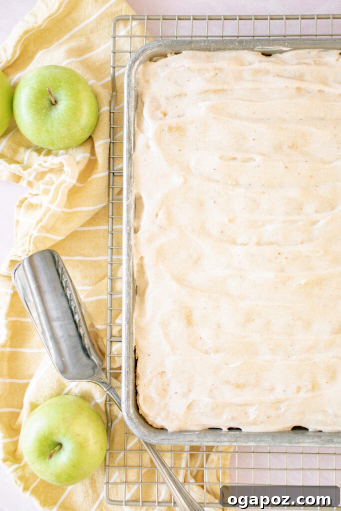 Autumn Apple Bars with Pumpkin Spice Glaze 8 A stack of freshly baked and iced Apple Bars with Pumpkin Pie Spice Icing, accompanied by a fresh apple, highlighting the perfect autumn dessert.