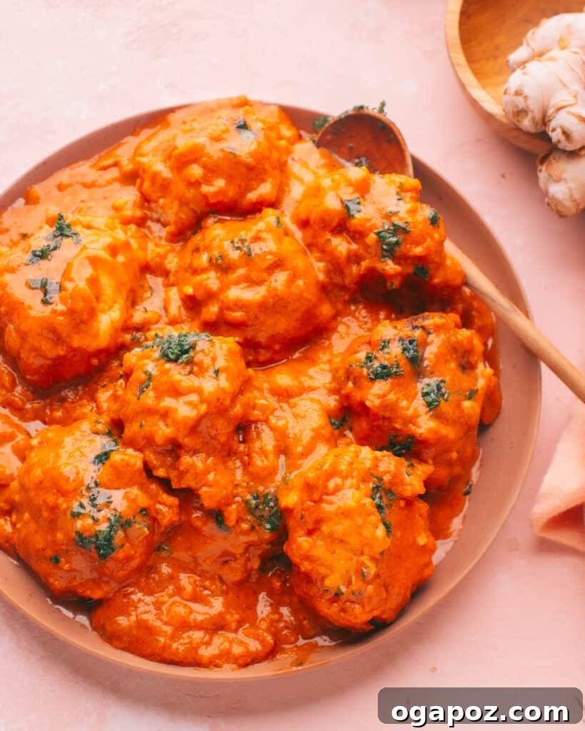 Effortless Creamy Paneer Kofta Curry 17 Malai Kofta in a bowl with a spoon, showing the creamy texture.