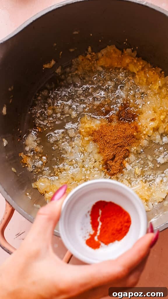 Effortless Creamy Paneer Kofta Curry 8 Adding powdered spices to the onion, garlic, and ginger mixture in a pan.