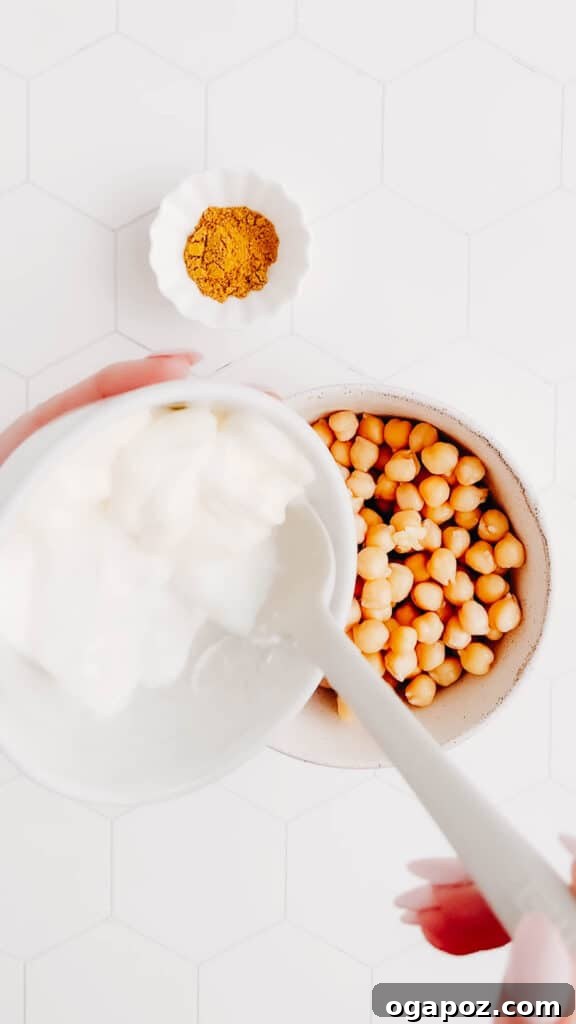 Elevate Your Wing Meal Side Dish Ideas 9 Adding yogurt and mayonnaise to a bowl of flavorful Indian Chickpea Salad.