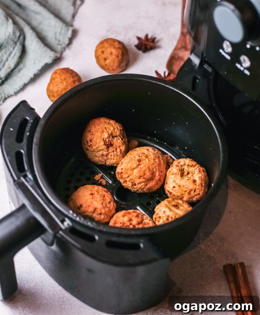Easy Air Fryer Donut Bites 3 Raw, unbaked pumpkin donut holes are carefully placed in the basket of an air fryer, poised and ready for cooking to golden perfection.
