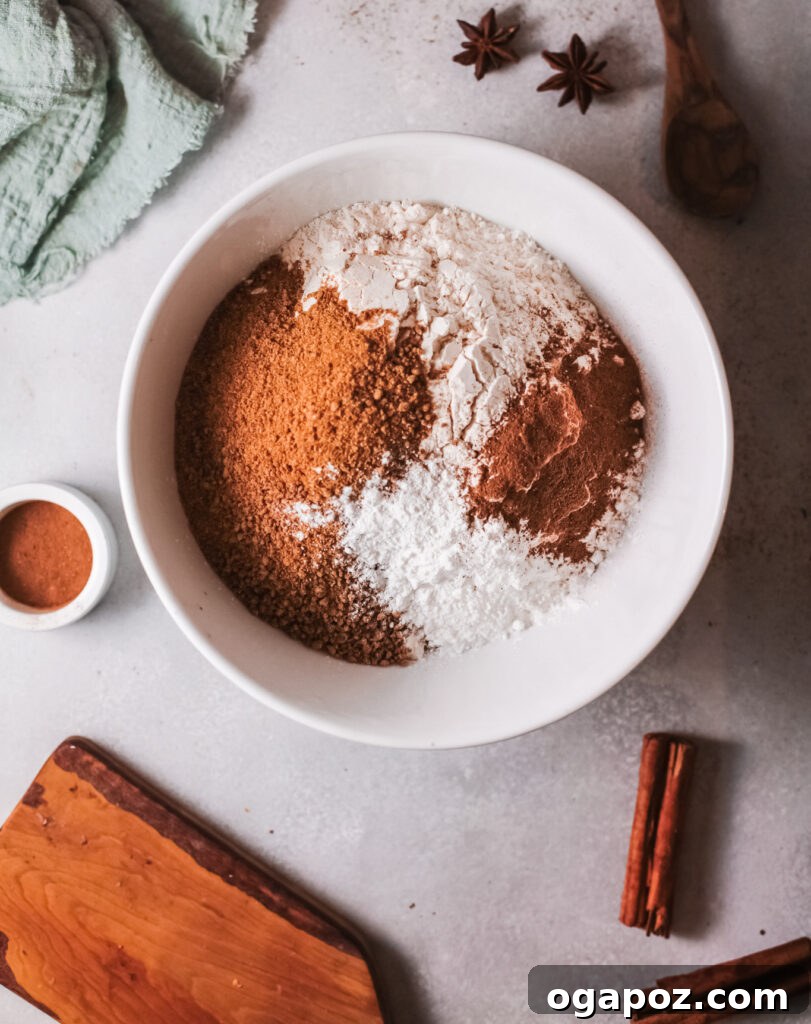 Easy Air Fryer Donut Bites 4 A large mixing bowl holds a perfectly blended dry mixture of flour, brown sugar, baking powder, pumpkin pie spice, and cinnamon, ready for the next steps.
