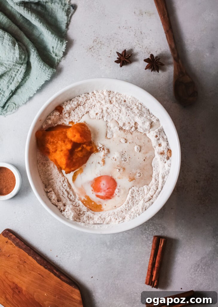 Easy Air Fryer Donut Bites 5 The bowl now contains the wet ingredients—pumpkin puree, vanilla extract, egg, milk, and oil—added to the dry mixture, ready to be combined into dough.
