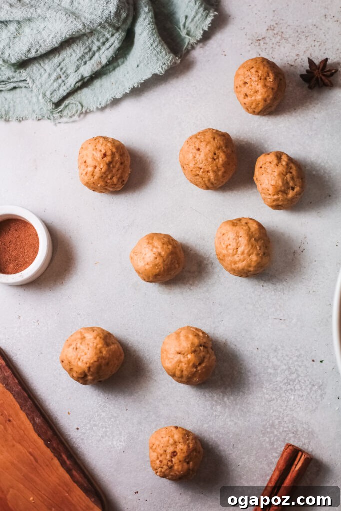 Easy Air Fryer Donut Bites 7 Twenty-five small, perfectly round donut holes are meticulously arranged on a parchment-lined cookie sheet, patiently awaiting their journey to the air fryer.