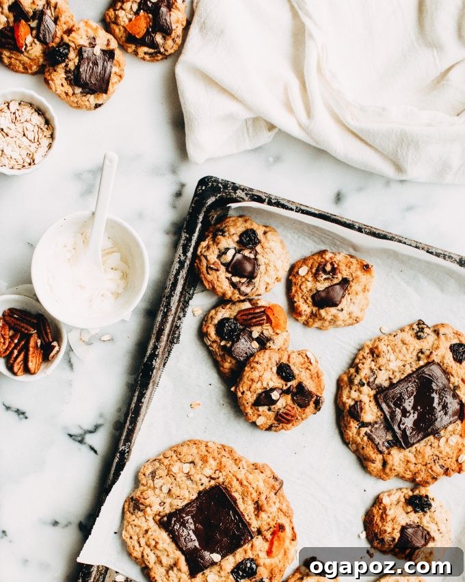 Epic Everything Cookies 4 Tray of freshly baked Giant Kitchen Sink Cookies cooling on parchment paper, showcasing their golden brown edges