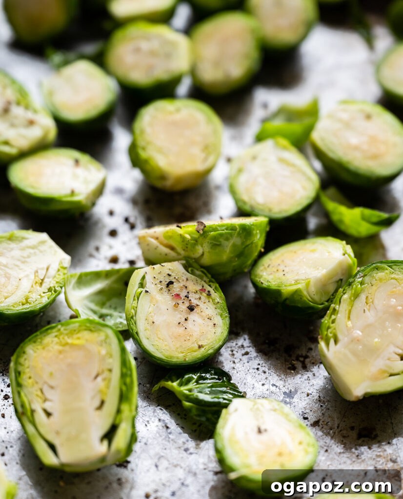 Balsamic Glazed Brussels Sprouts 5 Brussels sprouts tossed with olive oil, salt, and pepper, spread evenly on a baking sheet, ready for the oven.