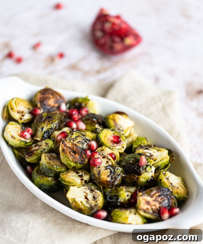 Balsamic Glazed Brussels Sprouts 8 A close-up of Roasted Balsamic Brussels Sprouts, perfectly glazed and garnished with ruby-red pomegranate arils in a white bowl.