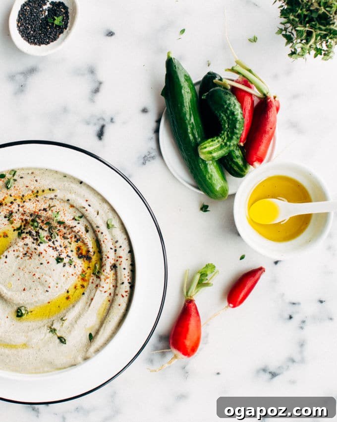 Black Tahini Hummus 5 A delicious bowl of creamy black sesame hummus garnished with a swirl of olive oil and extra sesame seeds, highlighting the dish's appealing texture and presentation.