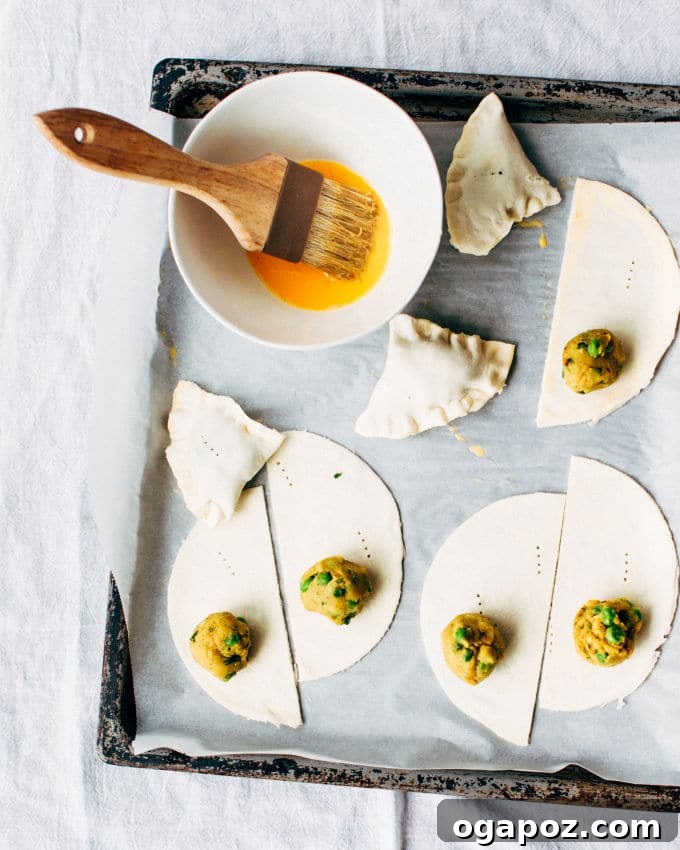 Effortless Flaky Samosas 9 Sealed puff pastry samosas brushed with egg wash, glistening and ready for baking to achieve a golden, flaky crust.