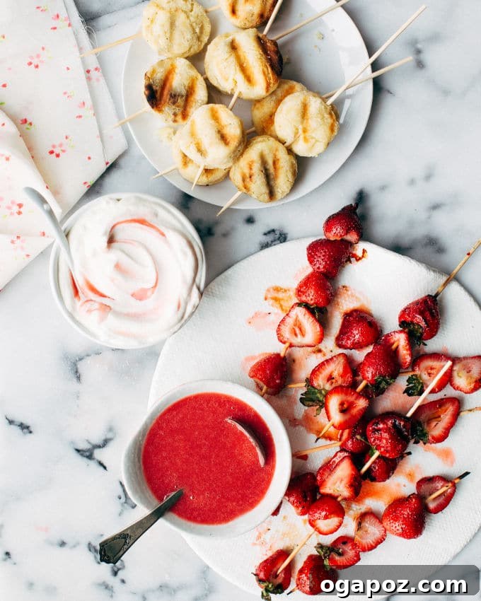 Flame-Kissed Strawberry Shortcake Sticks 3 A plate of grilled strawberry shortcake kebabs featuring juicy grilled strawberries, biscuits, whipped cream, and fresh sauce.