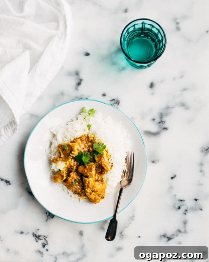 Fiery Goan Pork Vindaloo 7 A serving of easy Pork Vindaloo Curry on a marble counter with a blue glass, showcasing its rich texture and color.
