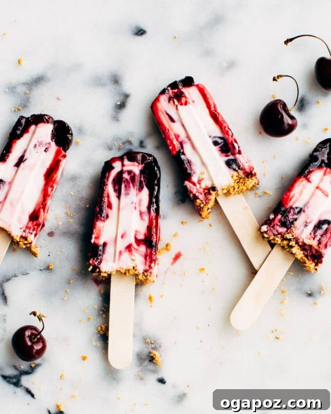 Delicious Cherry Cheesecake Popsicles with a vibrant cherry swirl and graham cracker crumbles, perfect for summer.