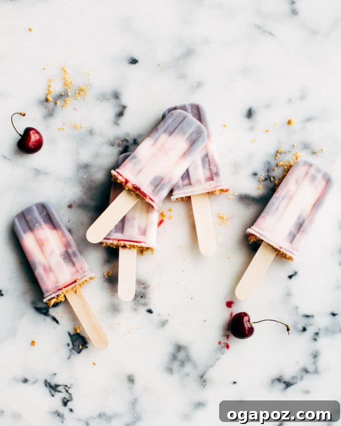 Close-up of Cherry Cheesecake Popsicles showing the creamy texture, distinct cherry swirl, and graham cracker topping.