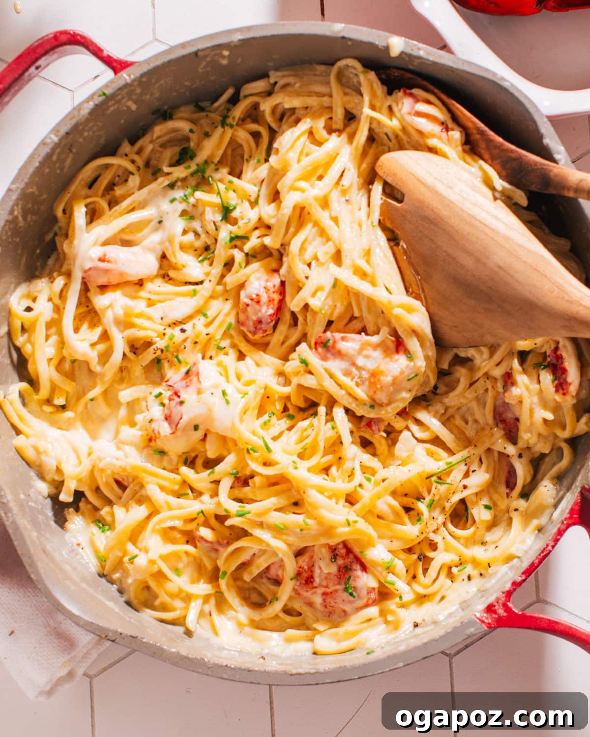 Luxurious Lobster Pasta with White Wine Cream Sauce 8 Finished Lobster Pasta dish in a white serving bowl with a spoon, garnished with fresh herbs.
