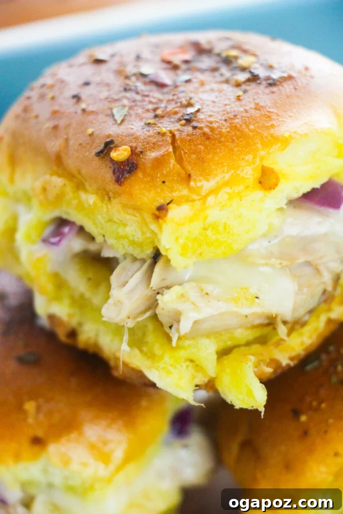 Effortless Chicken Sliders 6 Close-up shot of baked Easy Chicken Sliders with melted cheese oozing out, highlighting their delicious and golden-brown appearance.