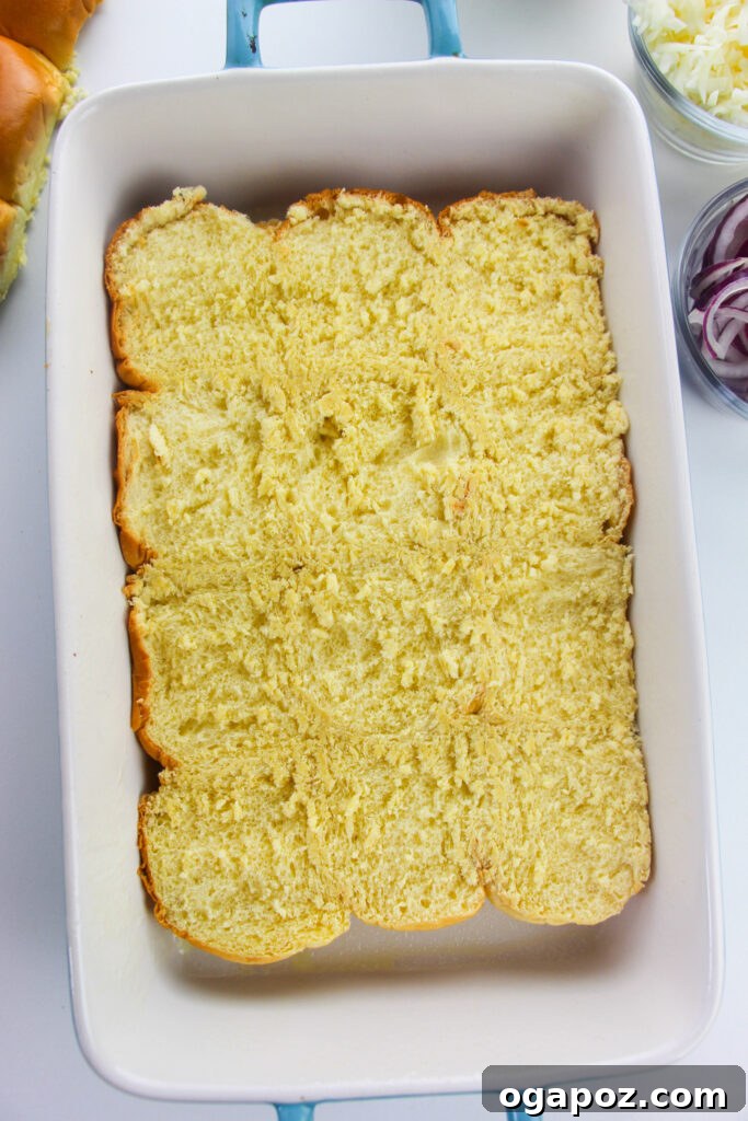 Effortless Chicken Sliders 7 The bottom half of a sheet of slider buns placed in a baking dish, ready for filling.