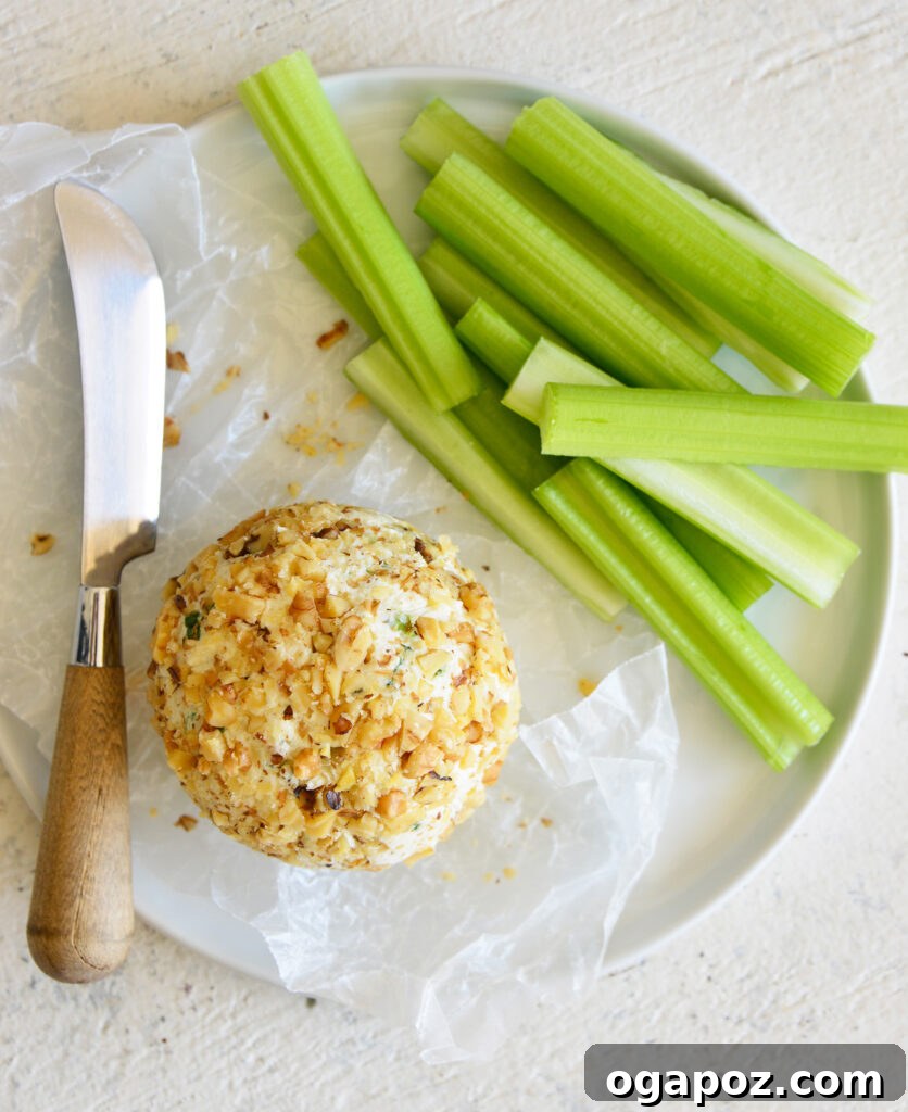 Your Guide to an Irresistible Cheese Ball 9 A festive cheese ball garnished with fresh herbs and served on a elegant white platter, surrounded by crackers and fruit slices.