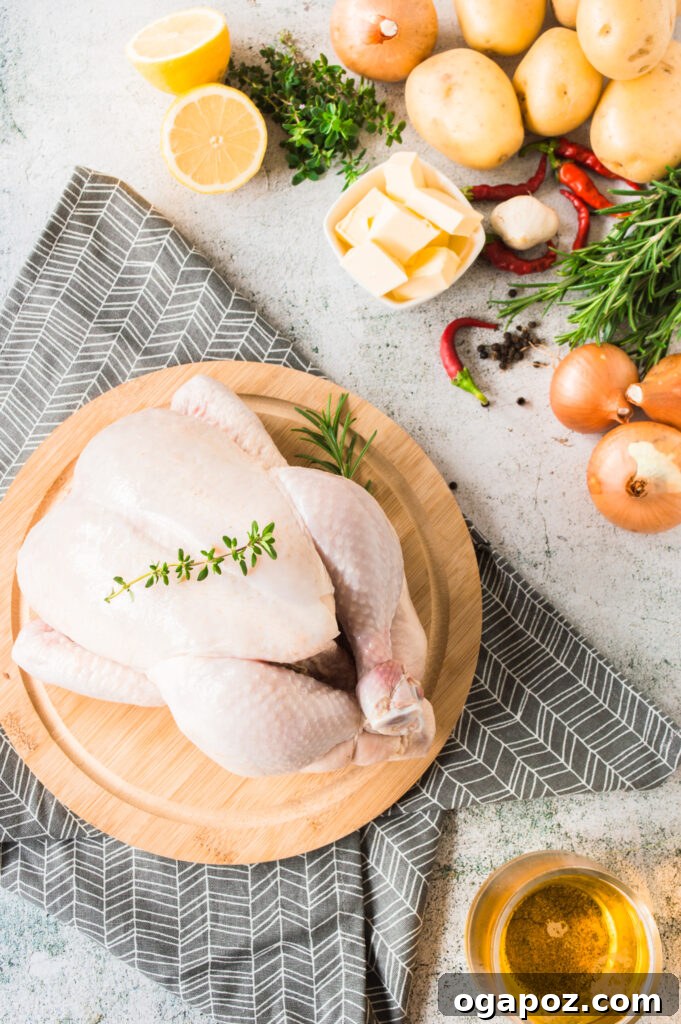 Golden Roasted Chicken with Crispy Herb Potatoes 4 Fresh ingredients for Whole Roasted Chicken with Potatoes including herbs, lemon, garlic, and butter laid out on a wooden cutting board
