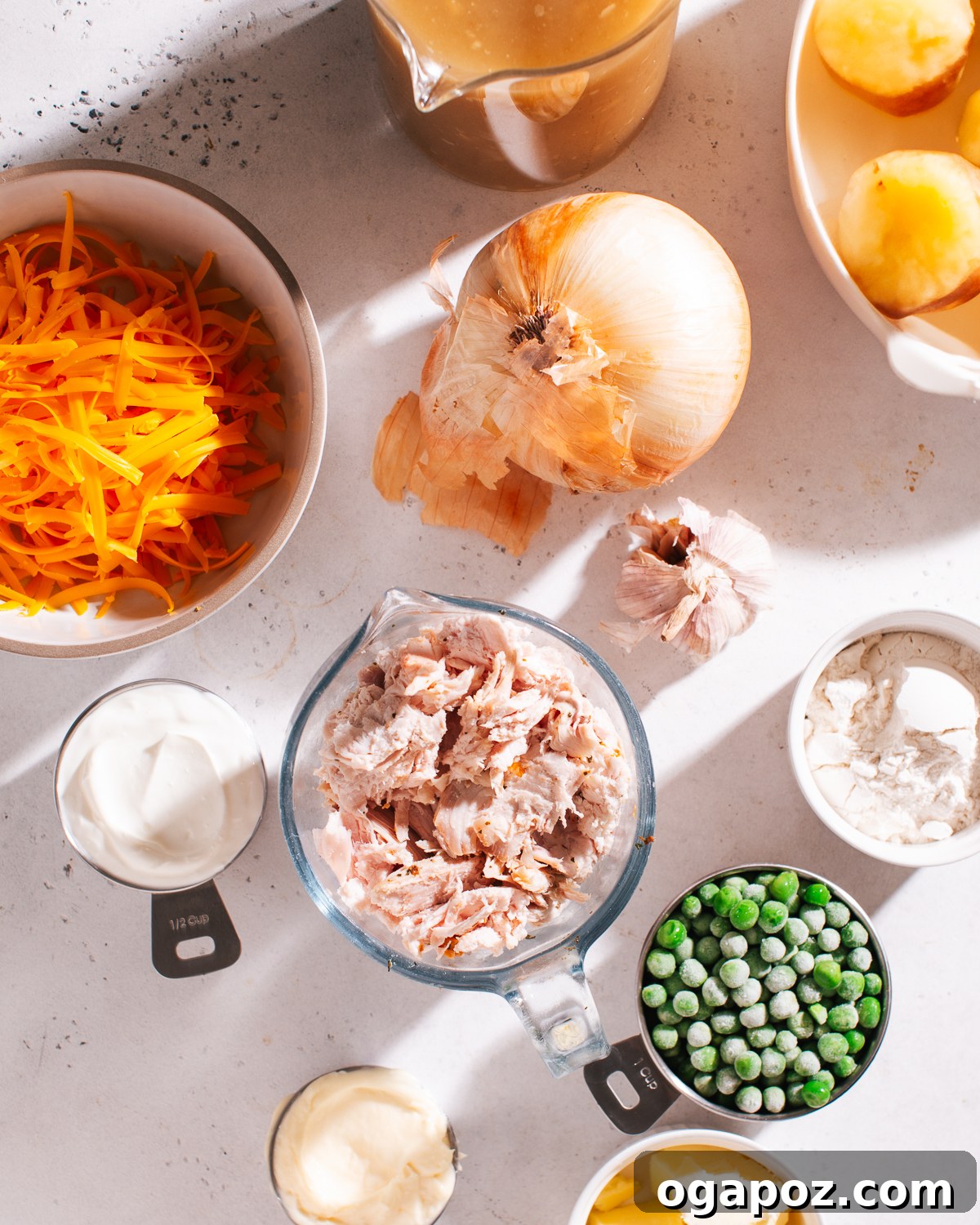 Effortless Comfort Chicken Potato Bake 3 Fresh ingredients laid out on a kitchen counter for making chicken potato casserole, including potatoes, chicken, cheese, and various sauces.