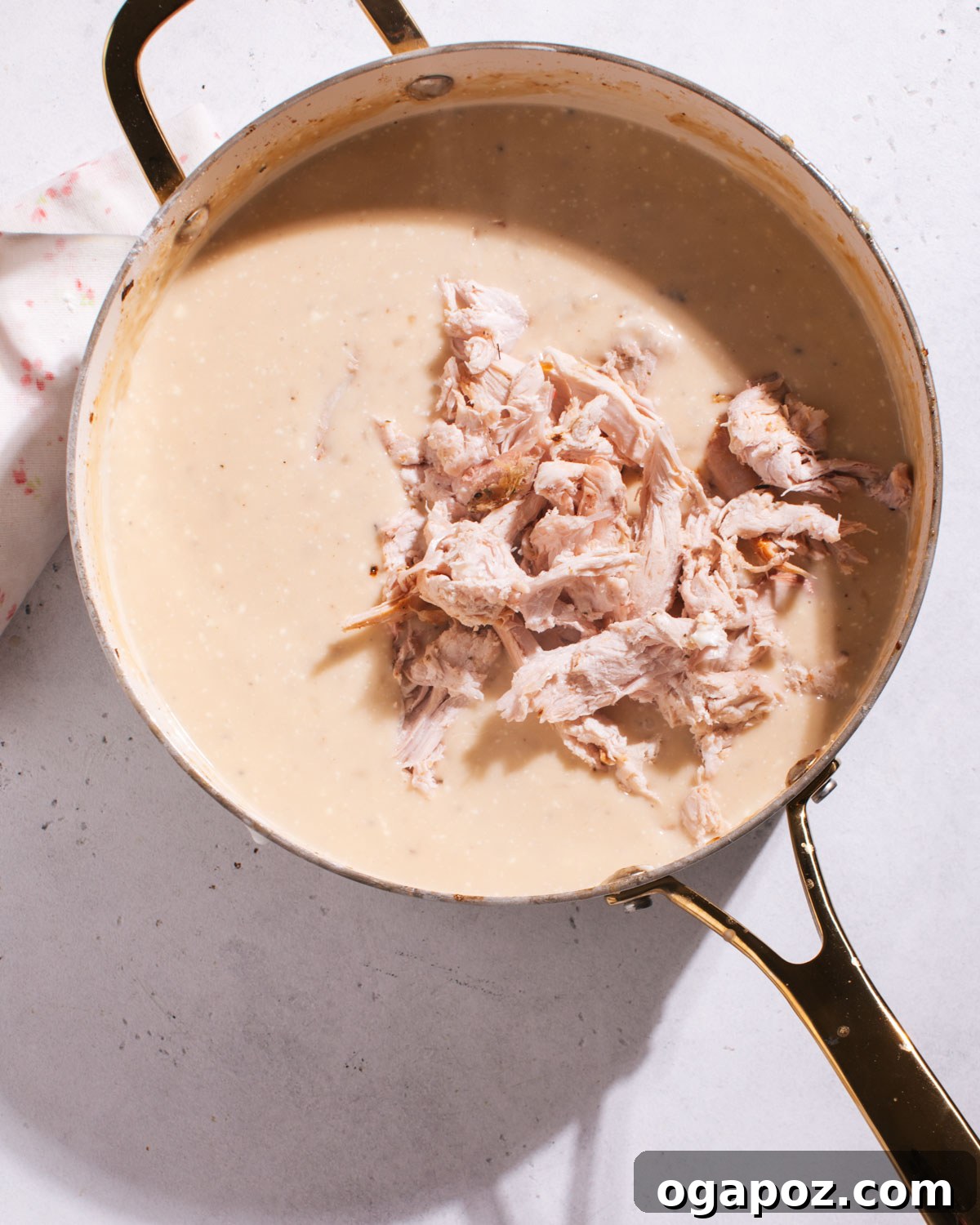 Effortless Comfort Chicken Potato Bake 5 Cooked chicken being gently folded into the creamy sauce in a large skillet.