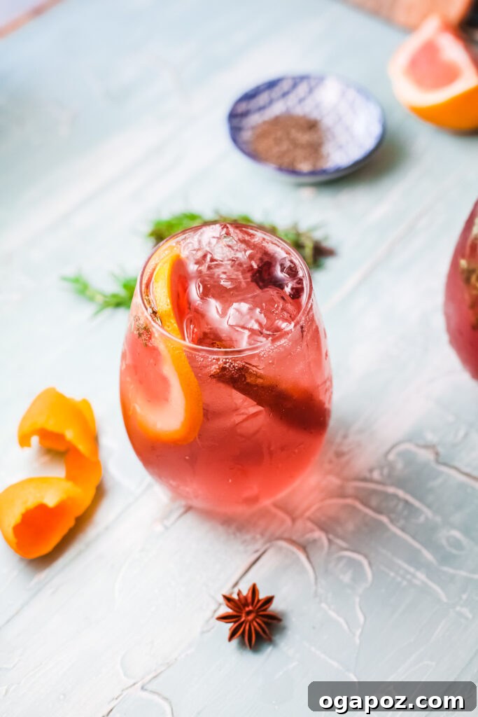 A beautifully garnished Cranberry Wine Spritzer in a tall glass, perfect for holiday gatherings