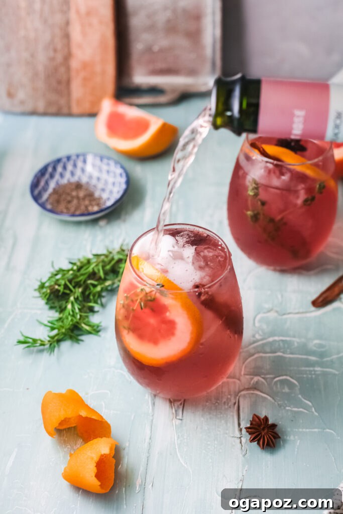 A glass of Cranberry Wine Spritzer topped with champagne bubbles and garnished with a blood orange slice