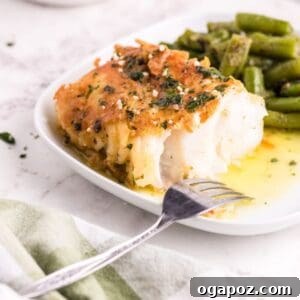 Pan-Fried Garlic Butter Cod on a white plate with a fork, drizzled with sauce