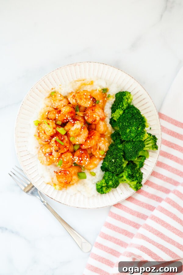 Sticky Sriracha Honey Garlic Shrimp 3 Honey Garlic Sriracha Shrimp artfully arranged on a white plate, garnished with fresh green onions and sesame seeds