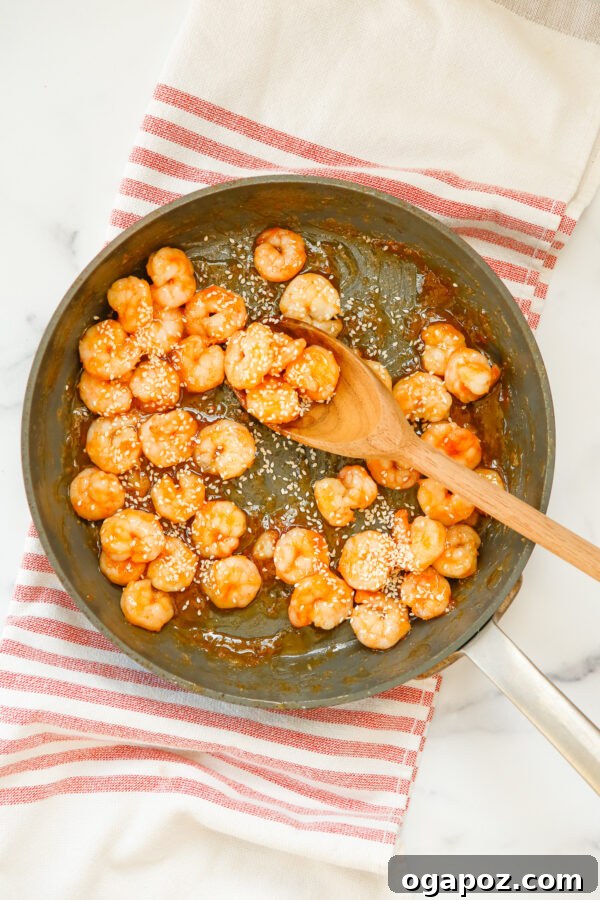Sticky Sriracha Honey Garlic Shrimp 7 Honey Garlic Sriracha Shrimp simmering gently in a skillet, coated in a thick, glossy sauce