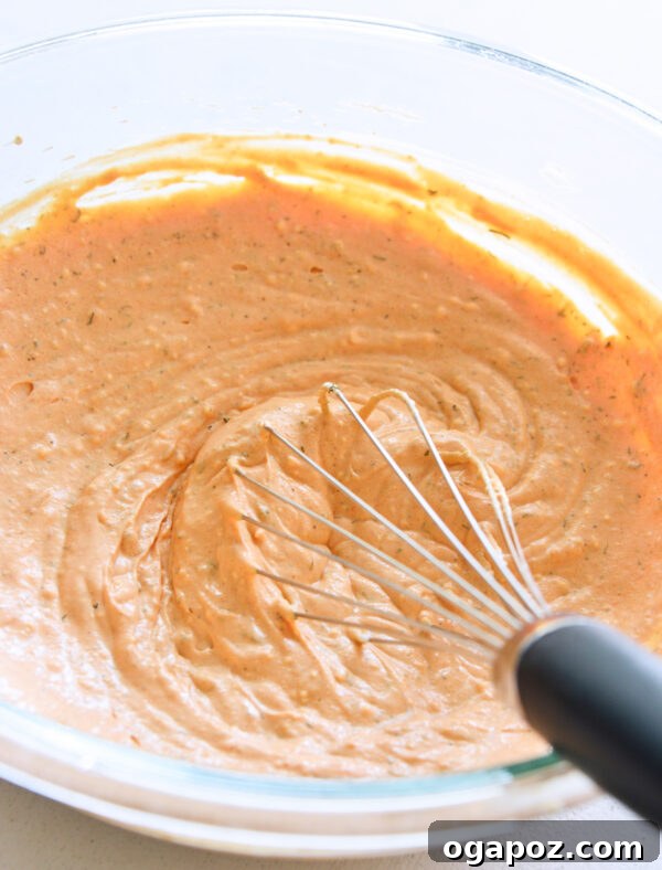Ultimate Buffalo Chicken Dip Recipe 5 Mixing cream cheese, sour cream, hot sauce, and spices in a bowl
