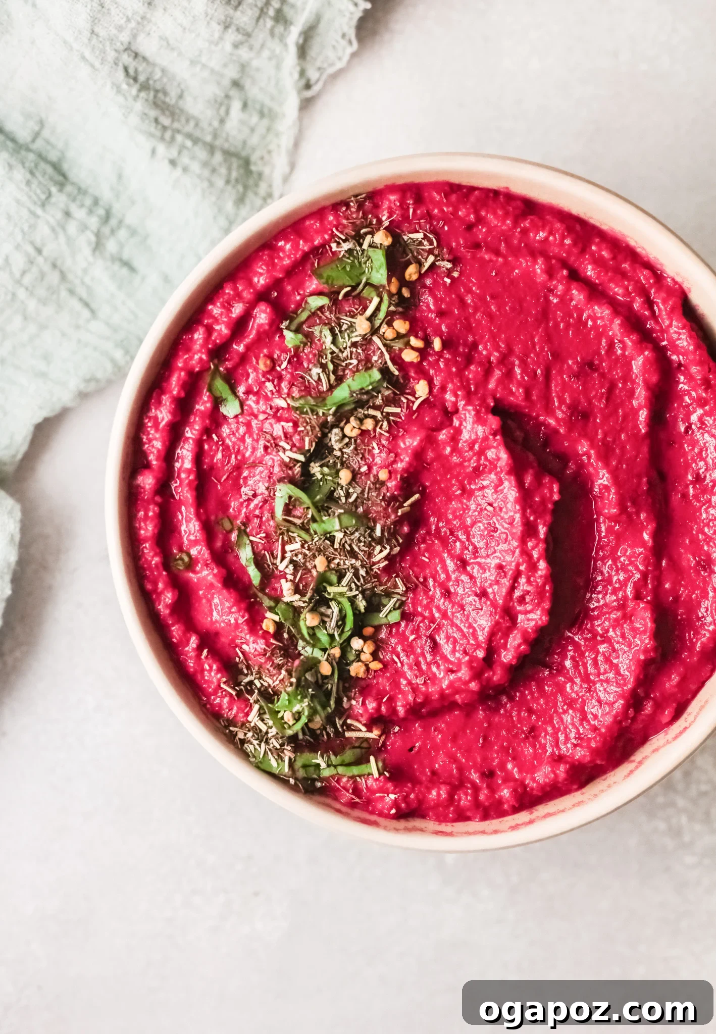Vibrant Beetroot Hummus 2 Easy Beet Hummus in a bowl, top shot, garnished with fresh herbs and olive oil