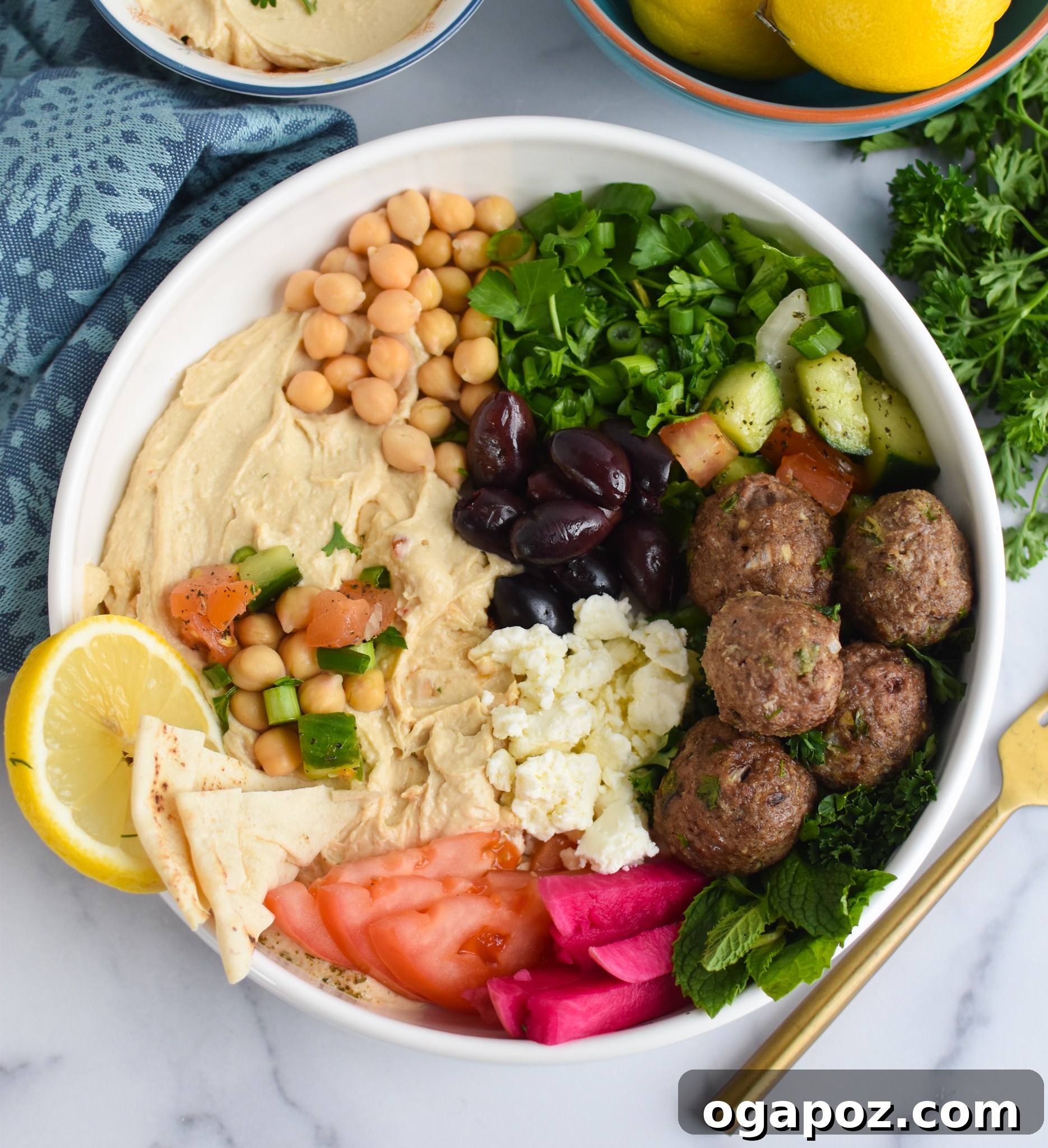 Spiced Lamb Kofta 3 Lamb Kofta served artfully with creamy hummus, crumbled feta cheese, fresh tomatoes, crisp cucumbers, and vibrant green onions.