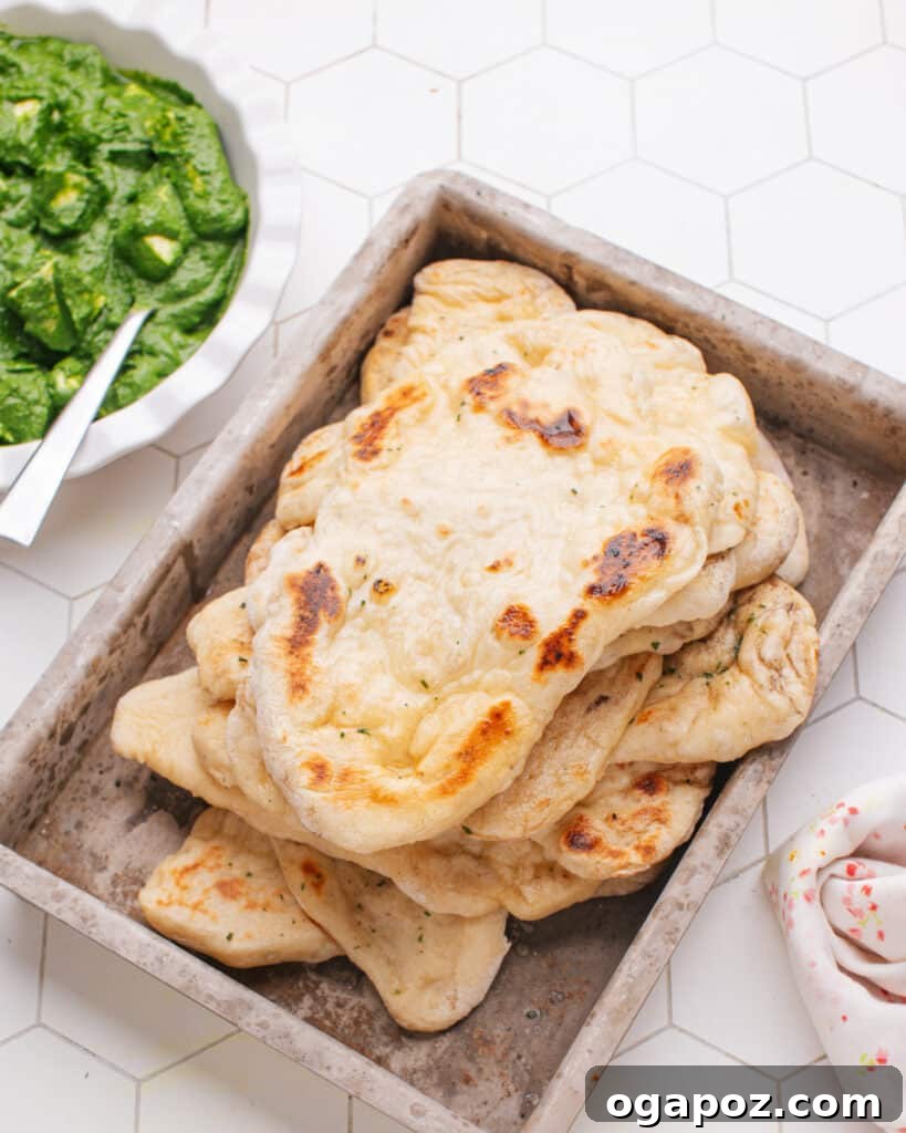 Pillowy Soft, Perfectly Stretchy Garlic Naan 9 Homemade Garlic Naan served alongside a bowl of rich Palak Paneer, a classic Indian spinach and cheese curry.