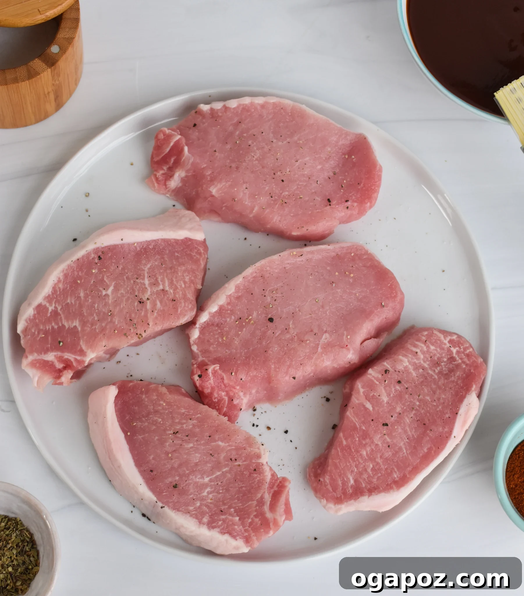 Succulent Oven Baked BBQ Pork Chops 5 Various ingredients for BBQ Baked Pork Chops laid out on a rustic wooden table.
