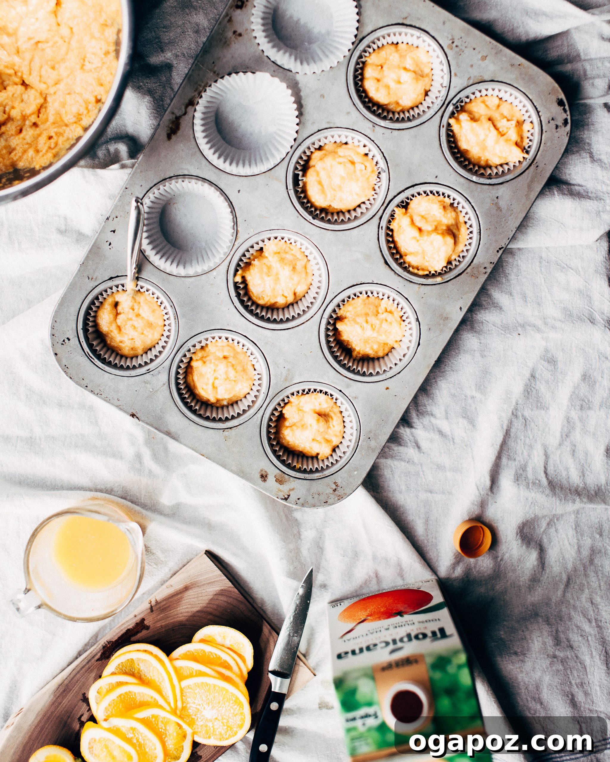 Zesty Orange Pumpkin Muffins 4 Multiple Pumpkin-Orange Muffins, each topped with a thin slice of fresh orange, arranged on a baking tray before baking.