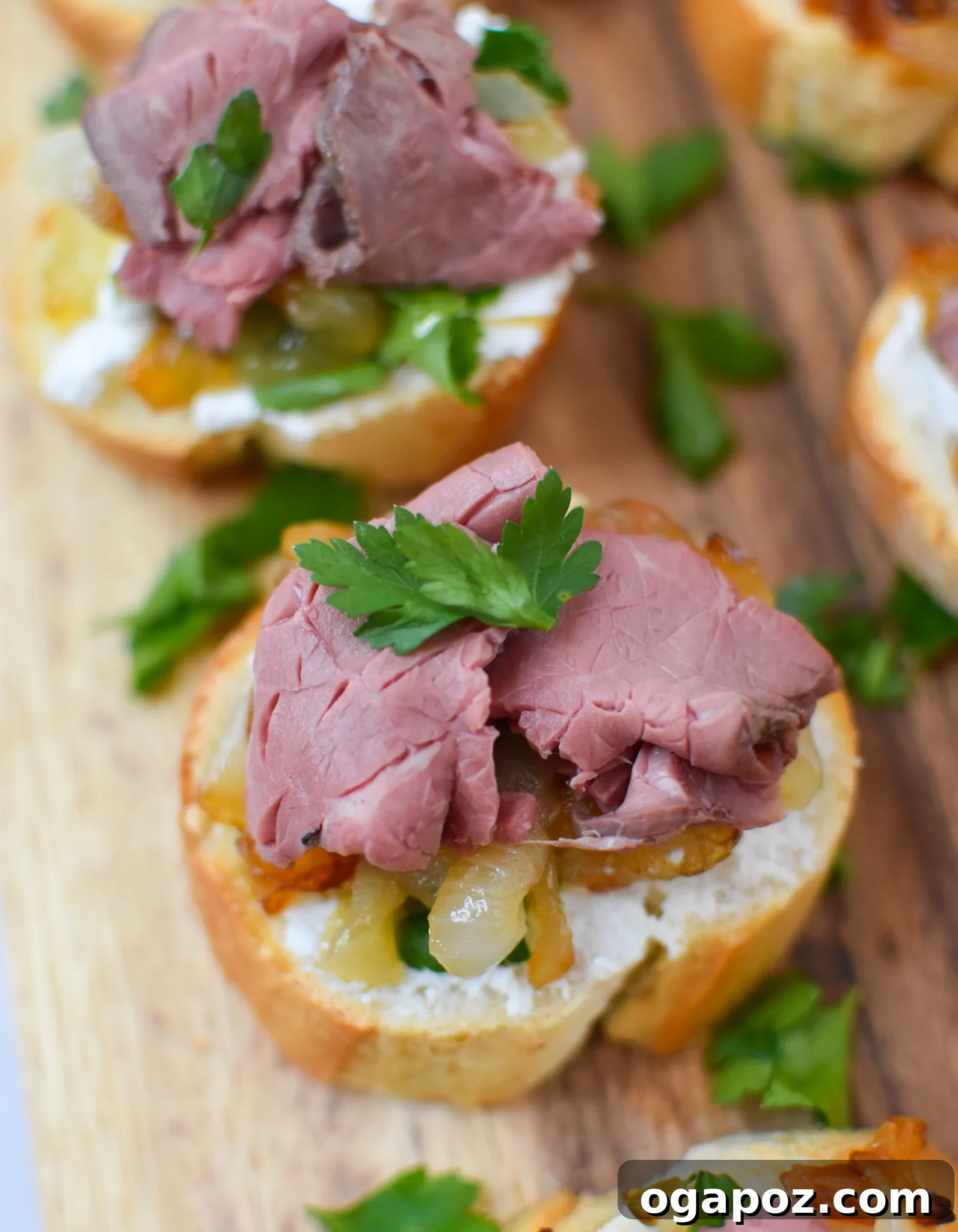 Gourmet Beef Crostini with Sweet Onion Jam 2 Beef Crostini with Caramelized Onion and Goat Cheese on a rustic wooden cutting board, ready to serve.