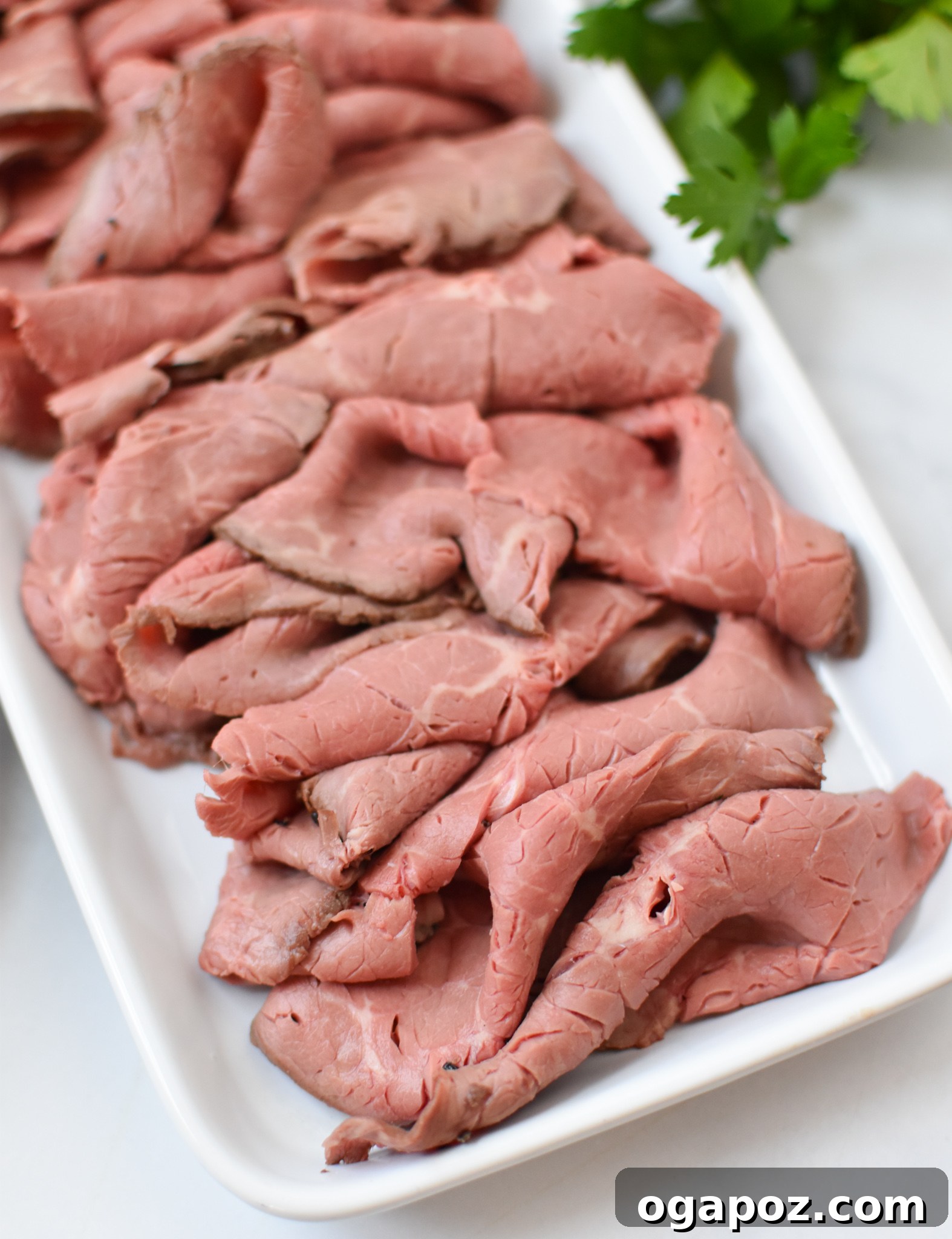 Gourmet Beef Crostini with Sweet Onion Jam 5 A perfectly cooked roast beef, thinly sliced and arranged on a plate, ready for the crostini assembly.