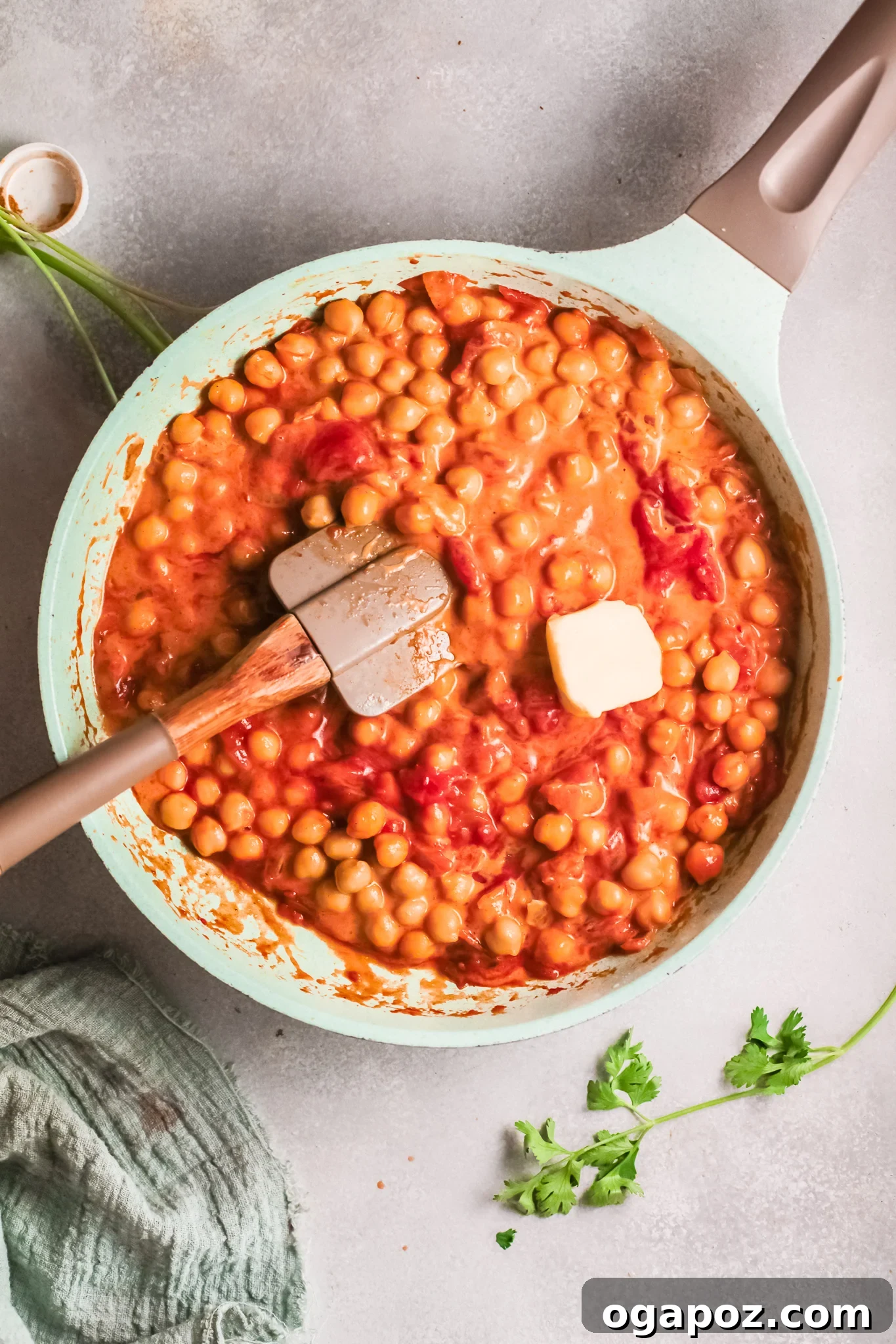 Golden Chickpea Curry 9 A knob of butter melting into the finished chickpea curry sauce in a pan, adding richness and a smooth texture.