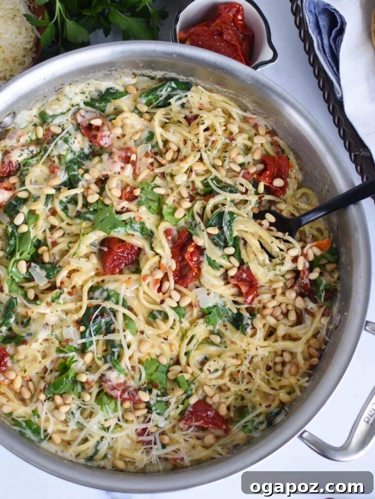 Luscious Creamy Sundried Tomato Pasta 2 Creamy Sun Dried Tomato Pasta Recipe with a spoon in the pan, garnished with fresh parsley.