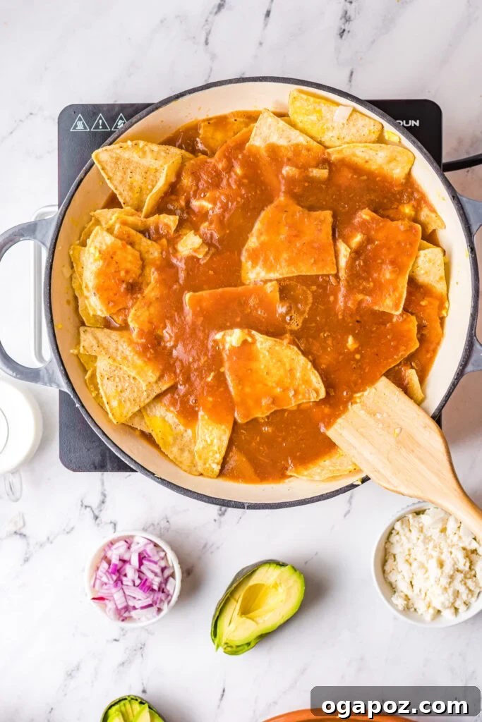 Authentic Mexican Chilaquiles Rojos 7 Tortilla chips and sautéed onions being tossed in a large skillet, ready for the sauce.