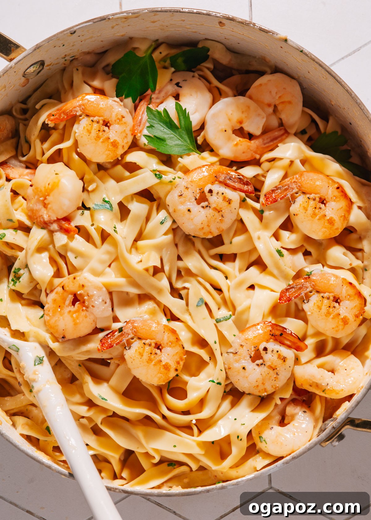 Zesty Lemon Cream Shrimp Pasta 2 Shrimp pasta in a large saucepan with a spoon, highlighting the creamy texture and vibrant ingredients.