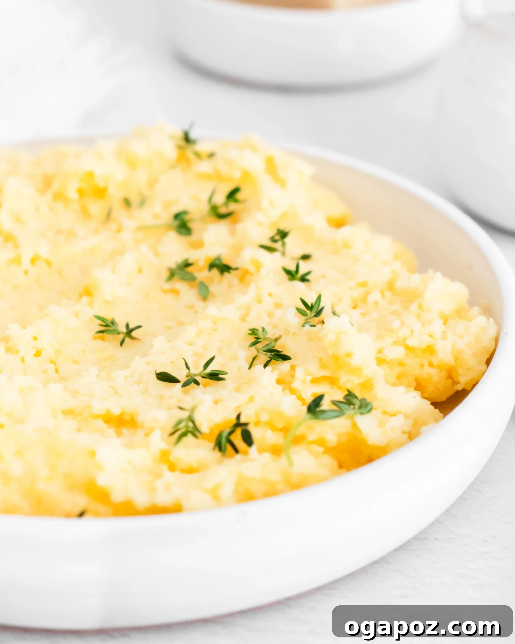 Dreamy Creamy Polenta 2 Creamy Polenta Recipe with fresh thyme in a bowl, showcasing its rich, creamy texture.