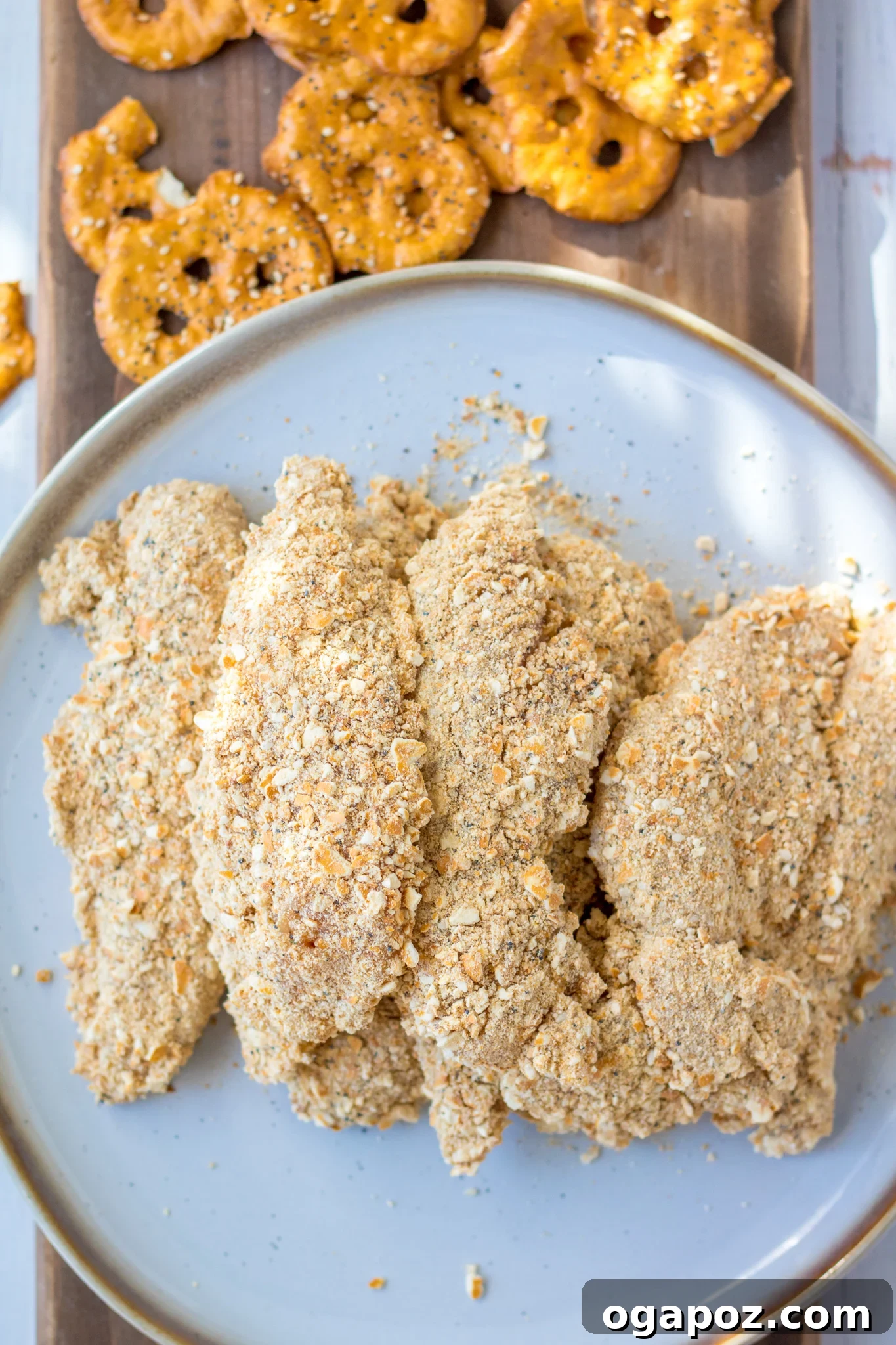 Crispy Pretzel Chicken Dinner 5 Several golden brown Pretzel Crusted Chicken tenders arranged on a white plate with a side of dipping sauce.
