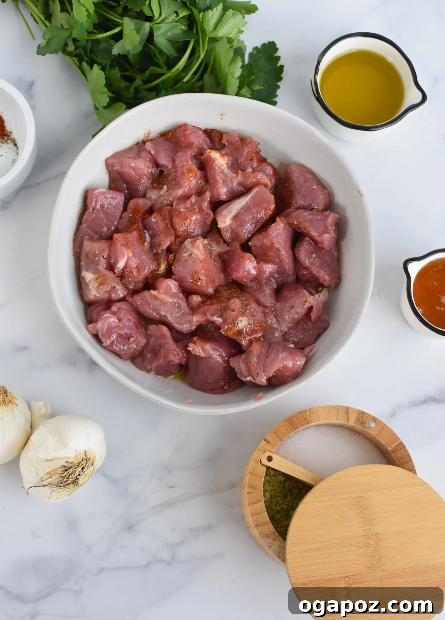 Perfectly Seared Cast Iron Pork Tenderloin 5 Prepared Cast Iron Pork Tenderloin ingredients, including seasoned pork cubes and minced garlic, displayed in separate bowls.