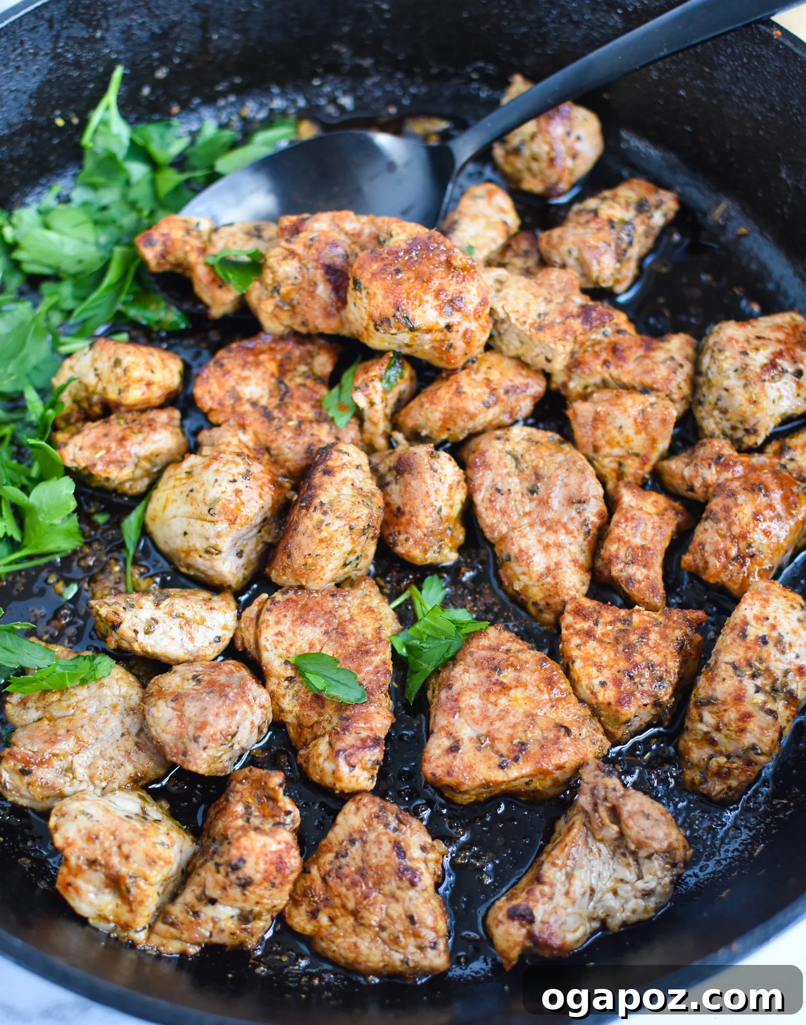 Perfectly Seared Cast Iron Pork Tenderloin 6 Cast Iron Pork Tenderloin cubes sizzling in a skillet, being stirred with a spoon, showing the browning process.