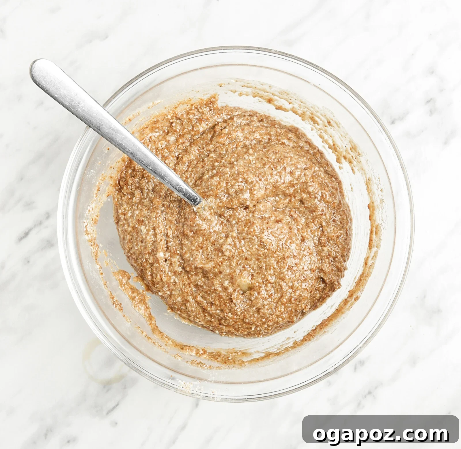 Soft-Baked Banana Oatmeal Cookies 6 Wet ingredients for Homemade Banana Oatmeal Cookies, including mashed banana, melted coconut oil, and almond butter, being added to a bowl with dry ingredients.