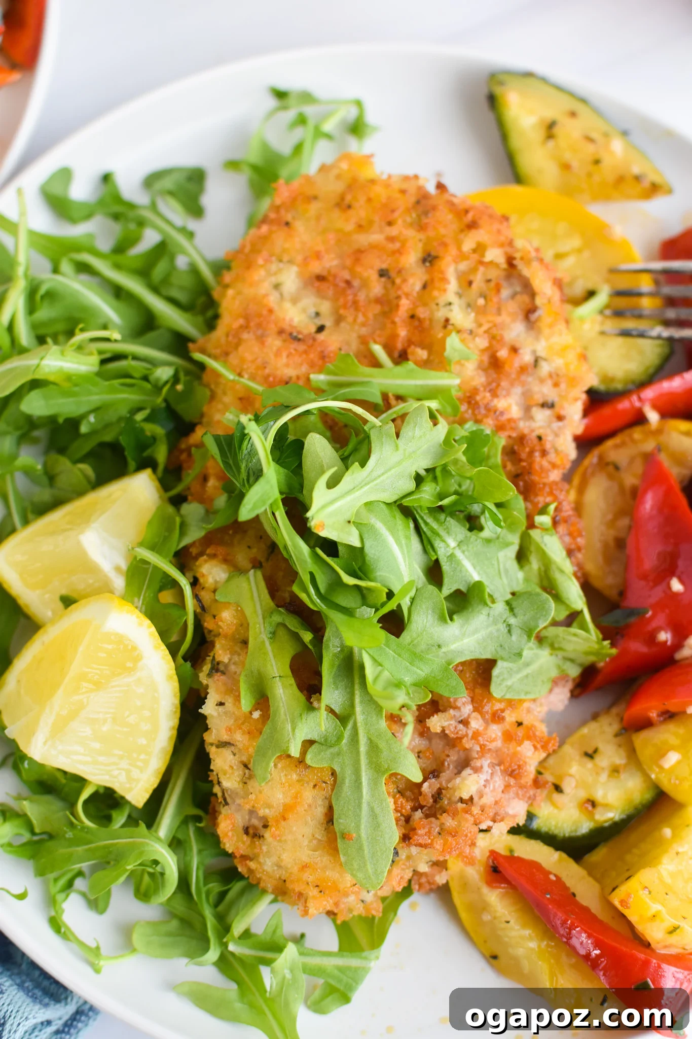 Easy Veal Milanese Recipe served with fresh arugula and lemon wedges.